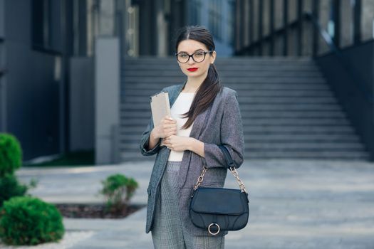 Businesswoman with specs wear grey elegant suit. Portrait of young businesswoman wearing glasses with a serious face.