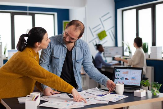 Brand manager asking for explication from employee in start up office discussion, Diverse team of business people analyzing company financial reports from computer.