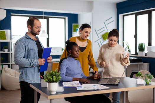 Diverse group of colleagues looking at laptop webcam during video conference meeting in start up company office. Multi ethnicity people enetrepreneur talking with client on online call. Successful start up corporate professional entrepreneur online internet statistics