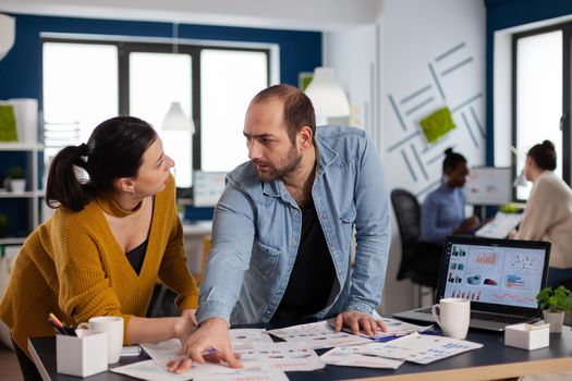 Businessman entrepreneur consulting with colleague working with charts during briefing. Diverse team of business people analyzing company financial reports from computer.