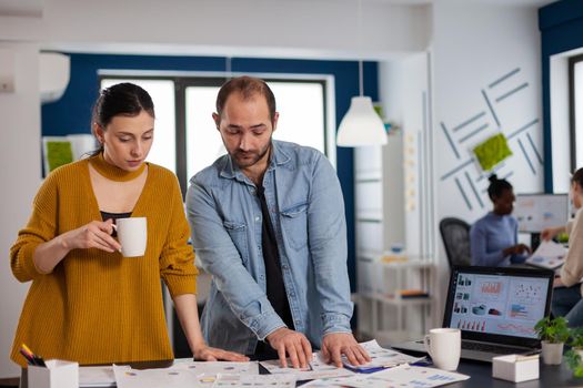 Multiethnic coworkers discussing in workplace statistic charts for briefing with management. Diverse team of business people analyzing company financial reports from computer. Successful start up corporate professional entrepreneur online internet statistics