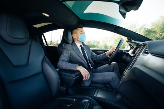 Businessman wearing medical mask in prevention for coronavirus and driving his car to work. Pandemic. Citizens. Lockdown safety. Businessman healthcare.