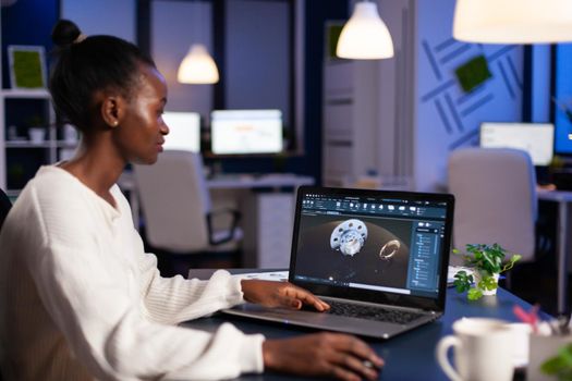 Black woman in mechanical industry working late at night doing overtime in start-up office. Industrial engineer studying prototype idea on pc showing cad software on device display.