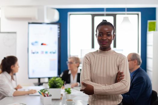 Successful smiling african business woman holding arms crossed looking atcamera in conference room. Manager working in professional start up financial business, modern company workplace ready for meeting.