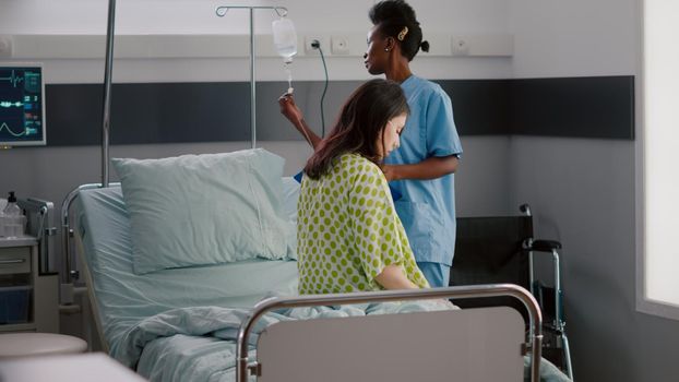 Afro american asisstant monitoring hospitalized sick woman with respiratory illness recovering after medical surgery. African nurse working in hospital ward explaining treatment to patient