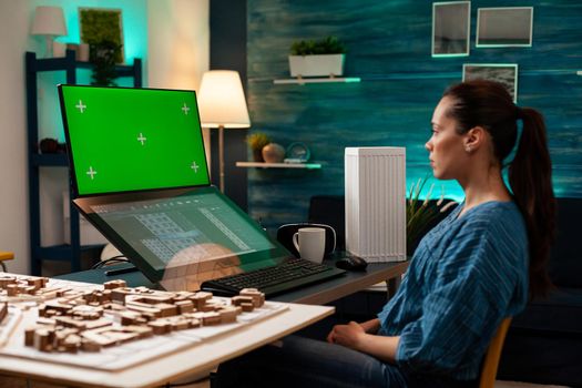 Engineer architect using green screen and blueprint on monitor computer screen at workplace. Woman doing manufacturing work on software template for development project design plan