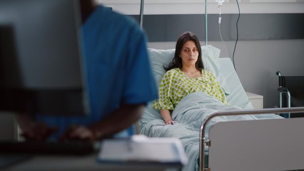 Front view of sick woman with nasal oxygen tube sitting in bed recovering after respiratory disease. Hospitalized patient waiting doctor for medical recovery treatment in hospital ward