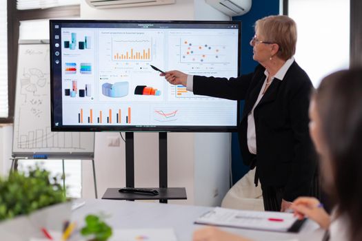 Businesswoman gives talk and speaking in conference room pointing at charts briefing. Corporate staff discussing new business application with colleagues looking at screen