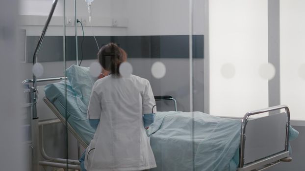 Patient lying in bed with oxygen tube discussing disease symptom to specialist practitioner doctor writing recovery treatment on clipboard. Medical nurse putting oximeter examining sickness expertise