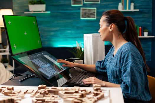 Architecture manager with design plan and green screen on computer monitor using professional equipment and tools. Woman working on blue print with isolated mockup background chroma key