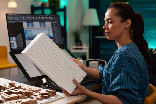 Construction architect holding modern maquette for building planning renovation at project workplace. Technical woman with digital blueprint using computer monitor screen for design