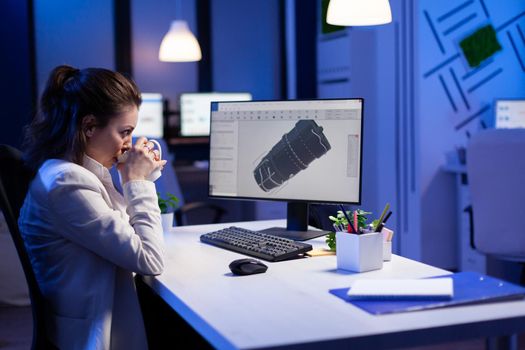 Woman engineer working late at night on 3D model of industrial turbine while drinking coffee in front of computer. Workaholic freelancer studying prototype design on pc showing cad software on device display