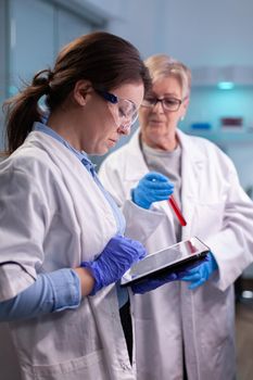 Doctors chemist researchers in white coat analysing blood test tube in equipped laboratory . Modern laboratory for scientific research with professional equipment for virus investigation working at vaccine development