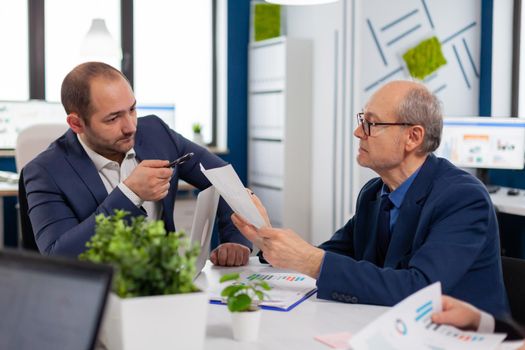 Senior entrepreneur discussing with coworker holding documents in conference during briefing Businessman discussing ideas with colleagues about financial strategy for new start up company.