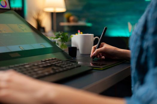 Close up of artistic hand using digital tablet and stylus while retouching image design at professional studio office desk. Woman doing editing work on editor software with modern equipment