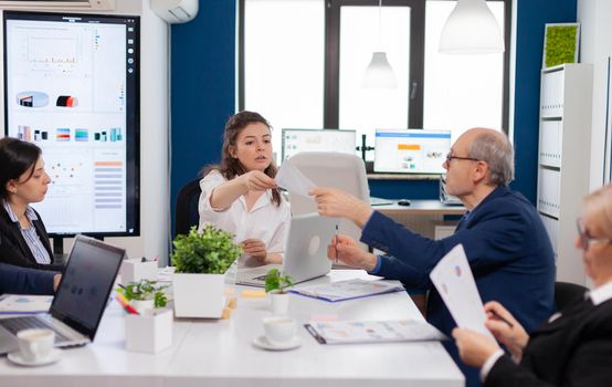 Team leader of start up giving tasks for multiethnic coworkers in company meeting room. Businesswoman discussing ideas with colleagues about financial strategy for new start up company.