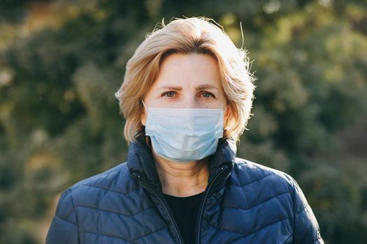 Woman Wearing Medical Mask During Coronavirus COVID-19 Epidemic. Sick woman wearing protection during pandemic. Pretty Caucasian Woman Taking on Medical Mask Outdoor