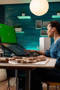 Development entrepreneur doing digital blueprint work on virtual maquette of building. Architect woman using green screen chroma key isolated mockup on monitor computer for industrial plan