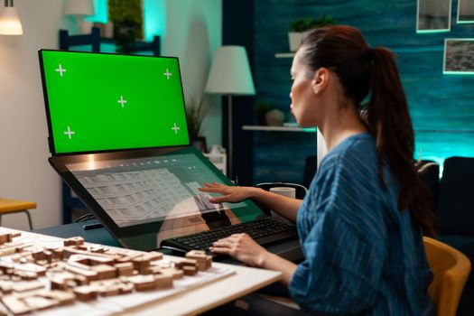 Development entrepreneur doing digital blueprint work on virtual maquette of building. Architect woman using green screen chroma key isolated mockup on monitor computer for industrial plan