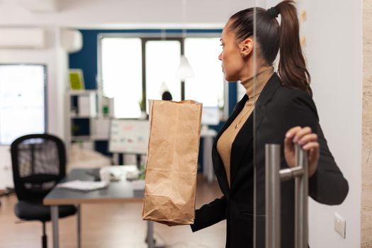 Businesswoman arrving at office with tasty delicious takeaway food in paper bag for lunch in corporate company office from delivery service. Manager with takeout fastfood.