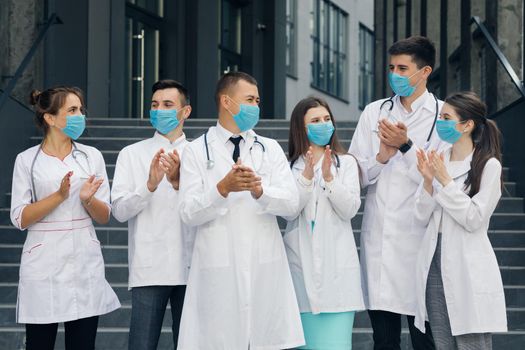 Medical staff from the hospital who are fighting coronavirus applaud back the people for their support. Alarm state. Corona Virus and Healthcare Concept. Doctors with face masks.