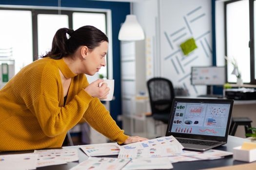 Corporate business woman in company office looking at statistics enjoying a cup of coffee. Executive entrepreneur, manager leader successful corporate professional entrepreneur working on online internet statistics