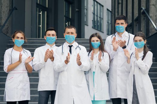 Corona Virus and Healthcare Concept. Medical staff from the hospital who are fighting coronavirus applaud back the people for their support. Group of doctors with face masks looking at camera.