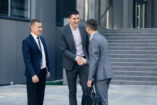 Group of Happy Men Corporate Workers Greeting Each Other Shaking Hands Starting Their Working Day in Contemporary Business District