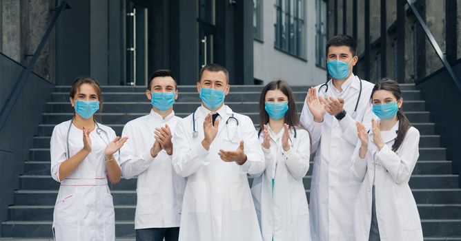 Corona Virus and Healthcare Concept. Medical staff from the hospital who are fighting coronavirus applaud back the people for their support. Group of doctors with face masks looking at camera