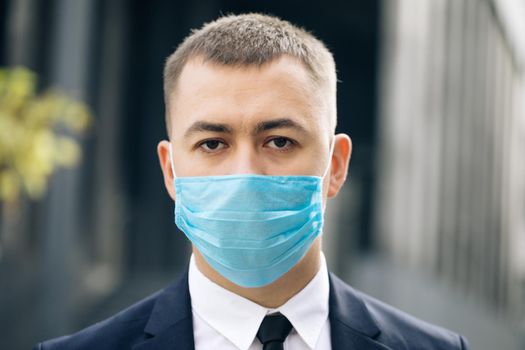 Portrait of a young businessman wearing protective mask on street. The concept health and safety, N1H1 coronavirus quarantine, virus protection. Pandemic Flu Corona Virus.