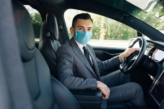 Adult businessman wearing medical mask in prevention for coronavirus and driving his car to work. Pandemic. Citizens. Lockdown safety. Businessman healthcare.