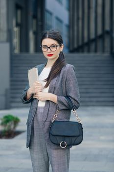 Attractive young businesswoman with specs wear grey elegant suit. Portrait of young businesswoman wearing glasses with a serious face