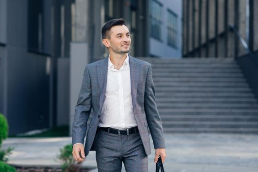 Modern businessman. Confident young man in suit looking away while standing outdoors with cityscape in the background. Handsome confident businessman portrait