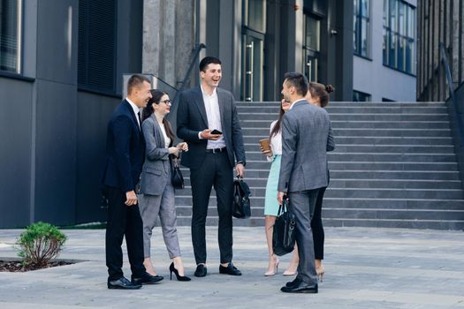 Male and Female Business People Discuss Business. Group of six young caucasian business people men and women meeting discussing outside office building.