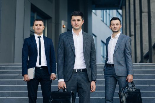 Confident businessmen with leather briefcase. Three business people standing on stairs