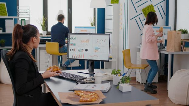 Entrepreneur woman having meal break sitting at table eating pizza slice fastfood delivery. Takeaway delivery lunch order package delivered at company office. Takeout food at lunchtime eating at desk