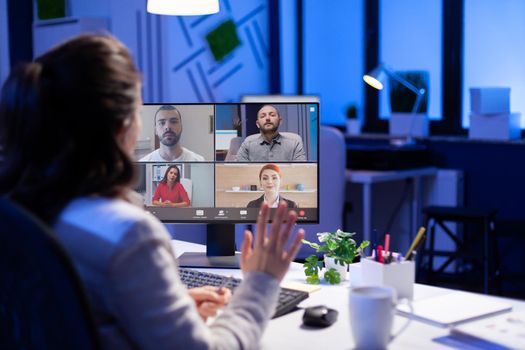 Manager during online video conference with corporate team after midnight using pc in start up business office. Videoconference internet meeting with technology network wireless discussing on video call late at night