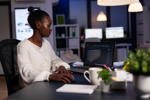 Black woman engineer designer looking at laptop analysing project using new software to design 3D concept of container working overtime in start-up company for prototype. Overworked worker studying.