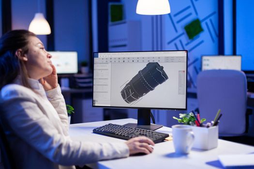 Project designer engineer analizing concept idea of 3D model of the plant yawning working overtime. Industrial woman worker studying turbine idea on pc showing cad software on device display