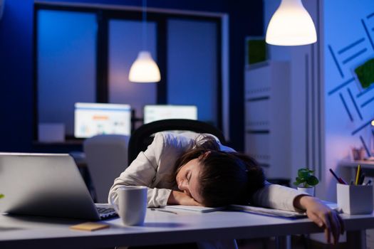 Entrepreneur working overtime on marketing project, falling asleep on desk while looking at financial documents trying to respect the deadline. Employee using modern technology network wireless