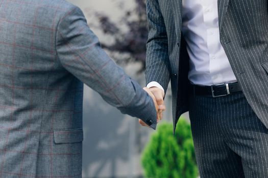 Hands of Top managers in Business Suits, shake hands with each other at Business center background. Agree to a deal or say hello. Unrecognizable person