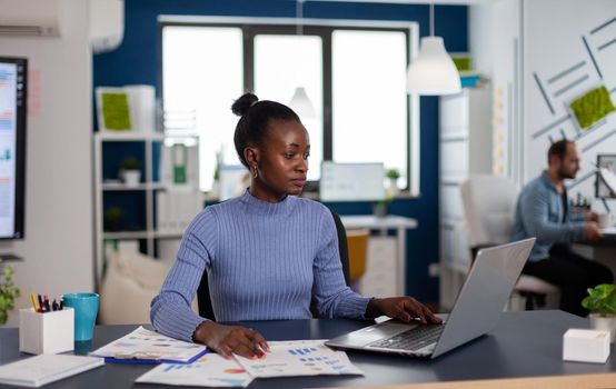 African manager and multiethnic team working to finish important project in startup office. Diverse team of business people analyzing company financial reports from computer.