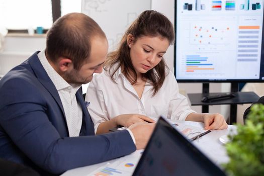 Colleagues of startup business discussing looking at documents in company board brainstorming conference room checking graphs and charts. Financial analysis during briefing.