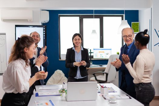 Happy creative business team having meeting in broadroom office victory overjoyed. Multiethnical partners coworkers celebrate successful teamwork result at company briefing