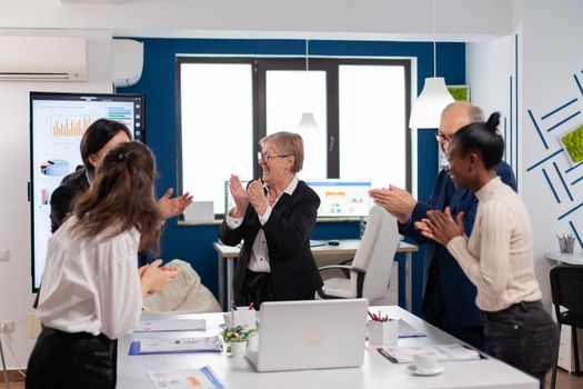 Happy excited diverse team of financial team in conference room after successful strategy. Multiethnical partners coworkers celebrate successful teamwork result at company briefing