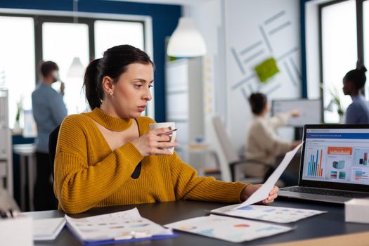 Team leadership of financial company reading charts in workplace drinking coffe. Executive entrepreneur, manager leader sitting working on projects with diverse colleagues.