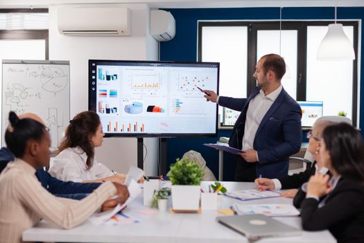 Manager holding briefing presentation in conference room monitor project. Corporate staff discussing new business application with colleagues looking at screen