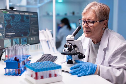 Pharmacy senior scientist working with professional microscope in clinic discovery. Modern lab with research equipment for virus study and vaccine science development