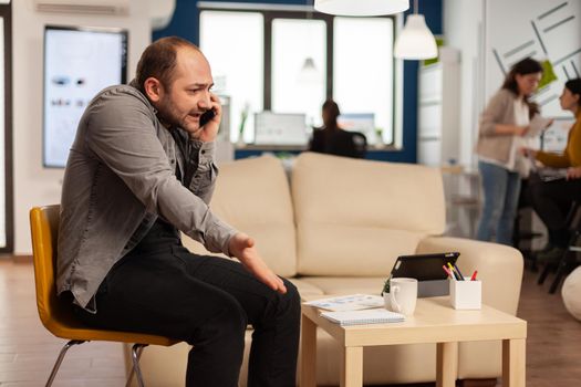 Frustrated desperate business man argue with another person in start up company during call phone. Stressed furious annoyed entrepreneur shouting yelling gesturing on work call. Coworkers working on project.