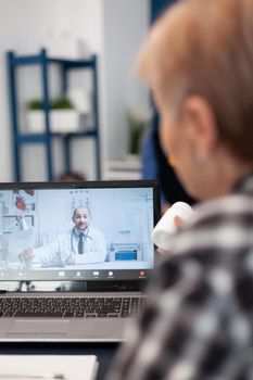 Old patient talking with doctor on virtual call showing pills bottle. Elderly woman on telemedicine online conference call with practitioner doctor using modern healthcare technology, web diagnosis